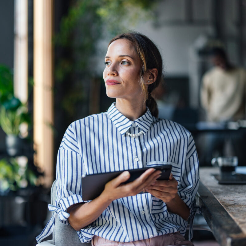 Professional Woman with Tablet Looking Thoughtful in Office