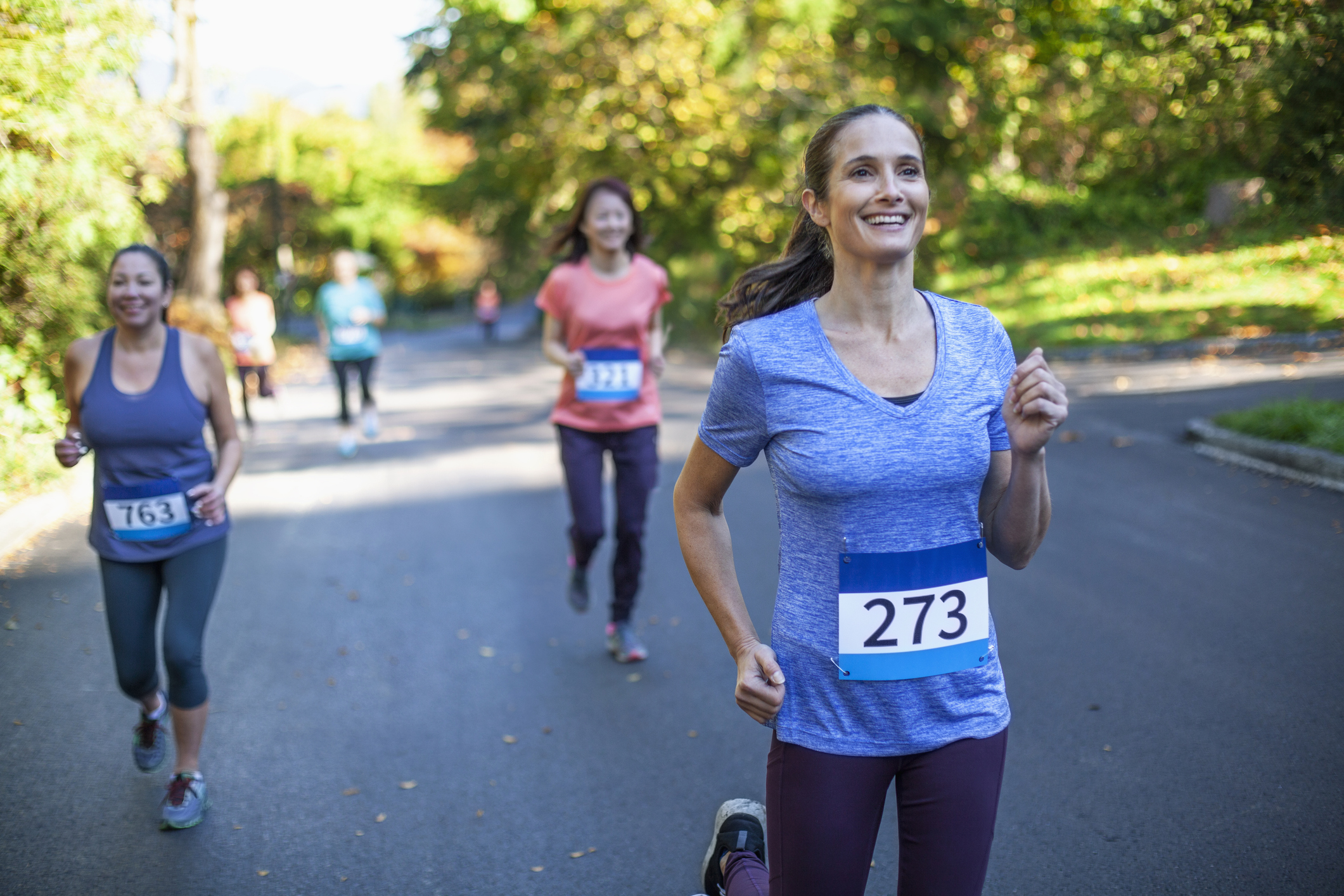 Mature multiracial woman runs in marathon race with group of women in park